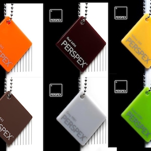 K&ouml;nnte beinhalten: Sechs verschiedene farbige Perspex-Muster, jedes mit einer silbernen Kette und einem Anh&auml;nger mit dem Perspex-Logo und dem Farbcode. Die Farben sind orange, rot, gelb, braun, grau und gr&uuml;n.