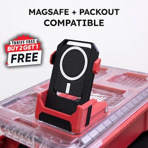 May include: A black and red MagSafe phone mount with a white circular design. The mount is compatible with Packout systems. The image also includes the text "MAGSAFE + PACKOUT COMPATIBLE" and a promotional sticker that says "TARIFF FREE BUY 2 GET 1 FREE".