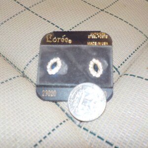 May include: A pair of gold oval earrings with blue and white stones, on a black card with the brand name "Lorée" and the text "Surgical Steel Posts Made in USA" and the number "23020".