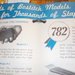 Puede incluir: Un anuncio vintage de grapadoras Bostitch, que presenta un primer plano de una peque&ntilde;a grapadora de mano y el texto "782" en una cinta azul y blanca. El anuncio destaca la variedad de modelos Bostitch disponibles para diferentes necesidades de grapado.
