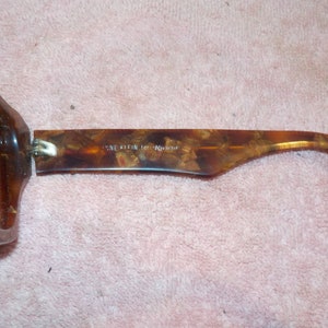 Puede incluir: Gafas de sol de carey marr&oacute;n con bisagra plateada y el texto "Anne Klein for K-Mart" en la varilla.