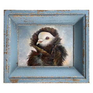 May include: An oil painting of a bird with a white head and red eyes, framed in a distressed blue wooden frame. The bird is depicted with brown and black feathers, set against a soft, light blue background.