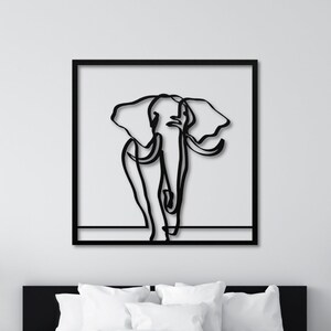 K&ouml;nnte beinhalten: Schwarz-wei&szlig;-Linienkunst-Illustration eines Elefanten in einem schwarzen Rahmen, der an einer wei&szlig;en Wand &uuml;ber einem wei&szlig;en Bett mit wei&szlig;en Bettw&auml;sche h&auml;ngt.