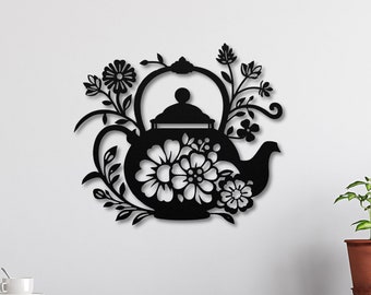 May include: Black metal wall art featuring a teapot with floral designs. The teapot is surrounded by stylized flowers and leaves. The art is mounted on a white wall above a kitchen counter.