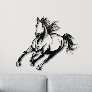 Op de afbeelding: Zwart-wit metalen wandkunst met een rennend paard. Het paard is in volle galop, met zijn manen en staart wapperend. Het kunstwerk is bevestigd aan een witte muur boven een grijze bank.
