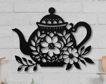 May include: Black metal wall decor featuring a teapot with floral details. The teapot has a rounded body, a spout, a handle, and a lid. The floral details are intricate and delicate, and they add a touch of elegance to the design.