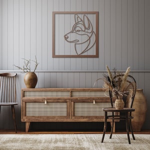 Pode incluir: Uma prateleira de parede de madeira com um design de arame cortado de uma cabe&ccedil;a de c&atilde;o em uma moldura marrom. A prateleira est&aacute; acima de uma c&ocirc;moda de madeira com quatro gavetas. A c&ocirc;moda tem uma frente de vime tran&ccedil;ado e puxadores de lat&atilde;o. Um vaso com galhos secos fica em cima da c&ocirc;moda, e uma cadeira de vime com um assento tran&ccedil;ado fica na frente da c&ocirc;moda.