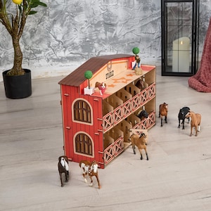 May include: A red wooden toy stable with the word "STABLE" on the roof. The stable has two levels with stalls and decorative cross-bracing. Several toy horses and a dog are positioned around the stable, creating a playful scene.