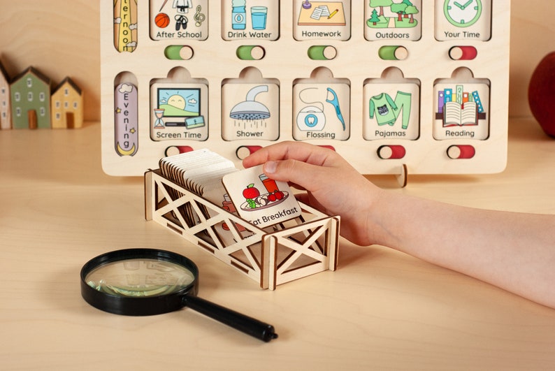 May include: A wooden visual schedule with a variety of activities for children, including screen time, shower, flossing, pajamas, and reading. The schedule has a slot for each activity and a toggle switch to indicate whether the activity is complete. The schedule also includes a small wooden box with a variety of activity cards.