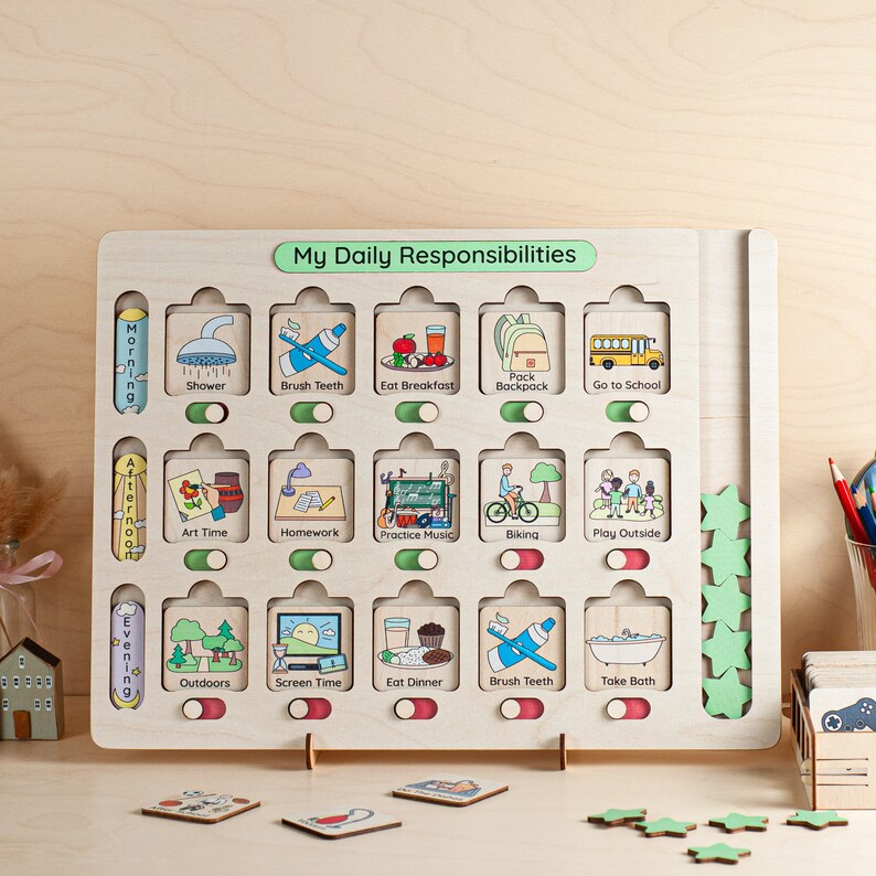 A wooden board with a green label that says "My Daily Responsibilities". The board has 18 squares with pictures of daily activities, such as showering, brushing teeth, eating breakfast, and playing outside. Each square has a toggle switch. There are also green stars on the right side of the board.