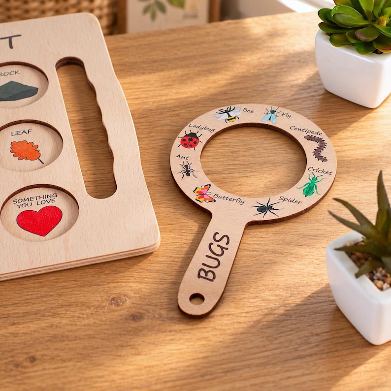 May include: A light-colored wooden magnifying glass frame labeled BUGS with illustrations of a bee, fly, centipede, cricket, spider, butterfly, ant, and ladybug, alongside a wooden board with circular cutouts for a rock, leaf, and heart.