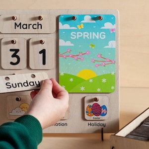 May include: A wooden calendar with removable pieces for the day, date, month, and day of the week. The calendar shows March 31st, Sunday, and a card with the word "SPRING" and a picture of a spring scene. There is also a card with the word "Holiday" and a picture of Easter eggs.