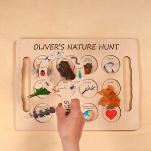Nature hunt board for babies and toddlers, designed for outdoor scavenger hunts and forest school activities. Montessori-style exploration tray encourages curiosity, observation, and sensory play. Perfect for collecting leaves, bugs, and natural treasures, with space for magnifying tools to support early nature learning and hands-on discovery.
