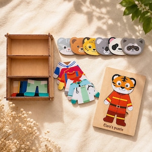 May include: A wooden dress-up puzzle set featuring a tiger character on a board labeled Clara's puzzle, a three-tiered storage shelf, six animal head cutouts, and several interchangeable colorful clothing pieces for the tiger figure.