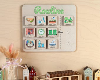 May include: Wooden routine chart with green "Routine" text and icons for daily tasks like lunch, flossing, and taking out the trash. Includes a wooden tray with small wooden blocks and miniature houses.