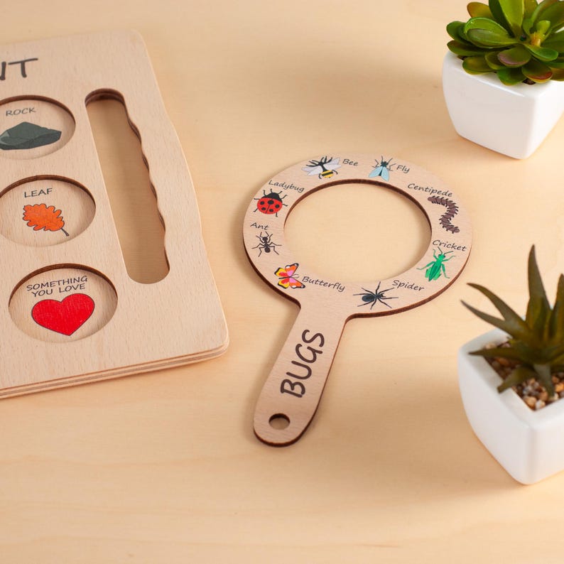 May include: A wooden nature scavenger hunt tool shaped like a magnifying glass with the word BUGS printed on the handle and illustrations of a bee, fly, centipede, cricket, spider, butterfly, ant, and ladybug around the circular frame.