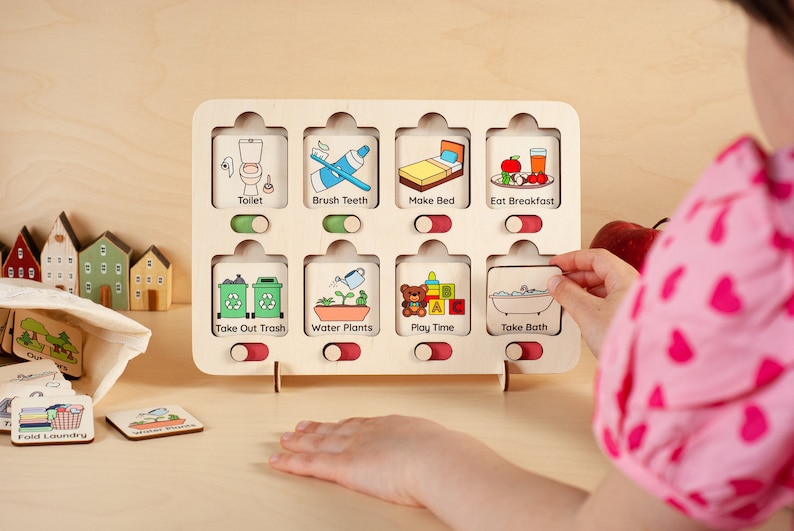 K&ouml;nnte beinhalten: Ein Holz-Aktivit&auml;tsbrett mit bunten Illustrationen und Textbeschriftungen f&uuml;r t&auml;gliche Routinen, wie "Toilette", "Z&auml;hne putzen", "Bett machen", "Fr&uuml;hst&uuml;ck essen", "M&uuml;ll rausbringen", "Pflanzen gie&szlig;en", "Spielzeit" und "Baden".