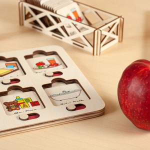 K&ouml;nnte beinhalten: Holzp Puzzle mit bunten Illustrationen von allt&auml;glichen Aktivit&auml;ten wie Schlafen, Essen, Spielen und Baden. Die Puzzleteile sind wolkig geformt und haben ein rot-wei&szlig;-blaues Farbschema. Ein roter Apfel liegt auf einer Holzoberfl&auml;che neben dem Puzzle.