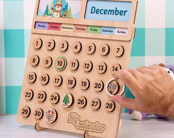 May include: A light-colored wooden perpetual calendar featuring the text "My calendar" at the bottom. It includes a top section with a snowman illustration and the word "December," a row of days of the week, and numbered circular wooden tokens.