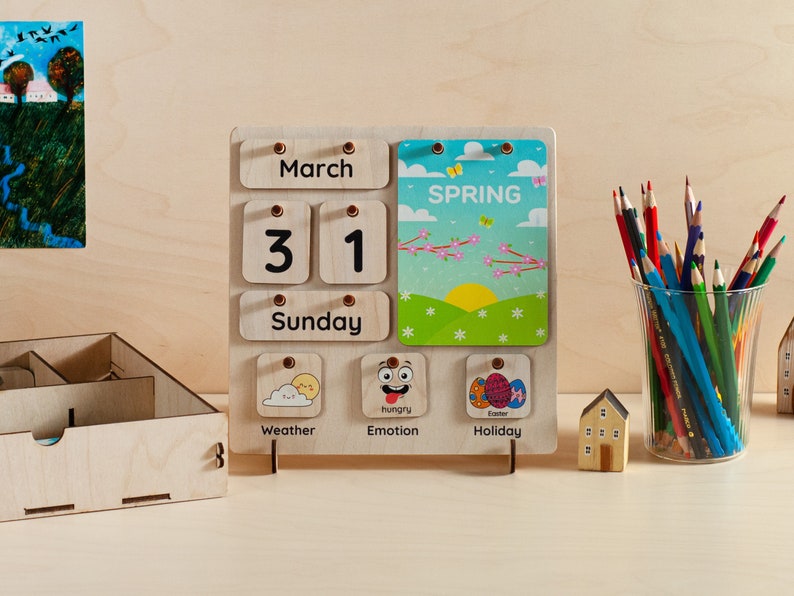 May include: A wooden calendar with a spring theme. The calendar shows the date 31st March, Sunday. The calendar also has a section for weather, emotion, and holiday. The holiday section shows an image of Easter eggs.