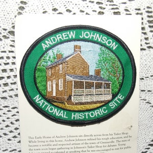 May include: A green and black embroidered patch with the words "Andrew Johnson National Historic Site" and an image of a brick house with a porch.