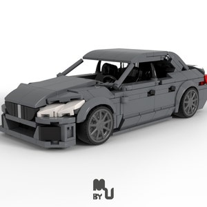 May include: A grey Lego model car with black accents and red tail lights. The car has a detailed interior and a sleek design.