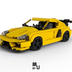 May include: A yellow Lego car model with black wheels and a black spoiler. The car has a detailed interior and a sleek design.