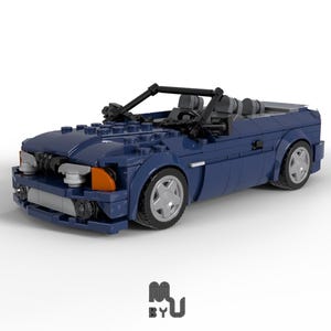 May include: A dark blue convertible Lego car model with black seats and orange headlights. The car has a detailed interior and exterior.