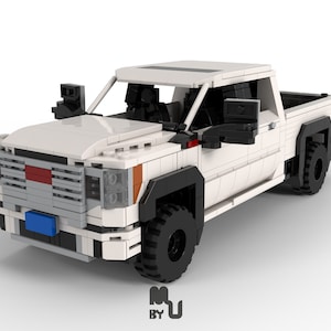 May include: White Lego pickup truck with black tires and side mirrors. The truck has a red and gray grill and a blue license plate.