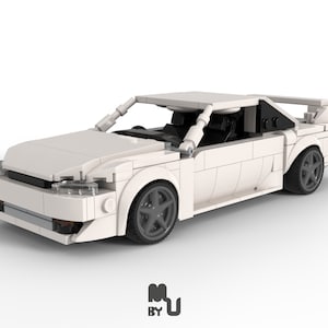May include: White Lego model car with black interior and black wheels. The car has a spoiler on the back.