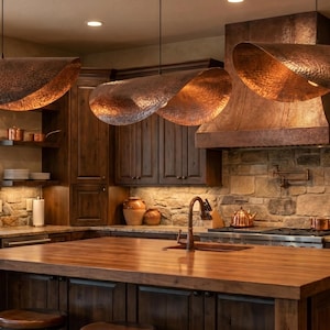 May include: A rustic kitchen with copper pendant lights, a wooden island, and dark wood cabinetry. The kitchen features a copper sink, range hood, and various copper cookware. The walls are a mix of stone and wood, creating a warm, inviting atmosphere.