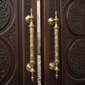 May include: Close-up of a pair of intricately carved wooden doors with ornate brass handles. The dark brown doors feature detailed geometric patterns and designs. The golden handles are vertical and cylindrical.