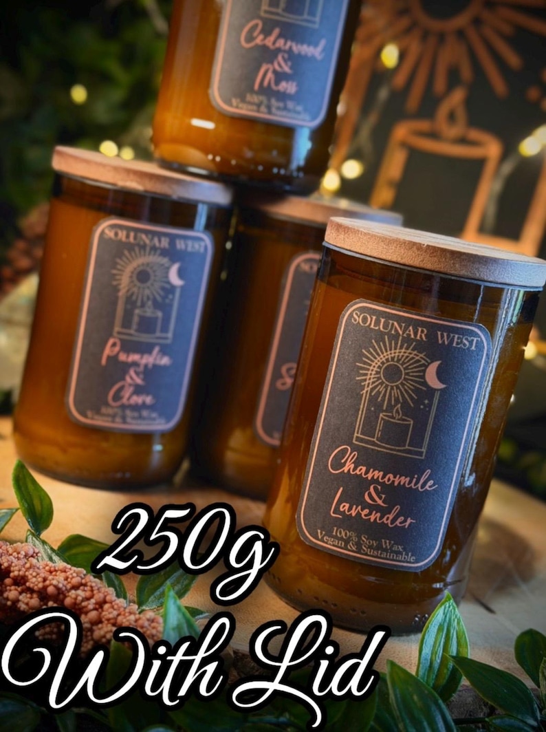 May include: Several glass jars of scented candles with wooden lids are stacked. Each jar has a label with the brand name "SOLUNAR WEST" and a different scent name, such as "Pumpkin & Clove" and "Chamomile & Lavender". The text "250g With Lid" is also visible.