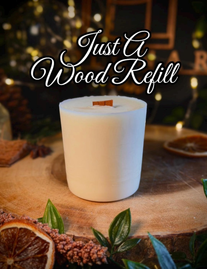 May include: A cylindrical white candle refill with a flat top and a single rectangular wooden wick centered in the wax. The text "Just A Wood Refill" is displayed in a white cursive font with a black outline above the candle.