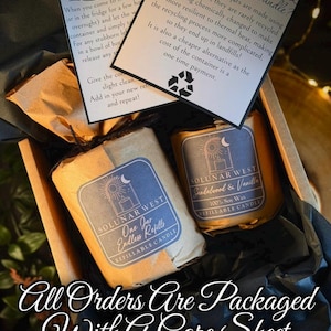 May include: Two refillable soy wax candles wrapped in brown paper with dark blue labels featuring a sun and moon logo, labeled Solunar West. Includes a printed care sheet with instructions on candle maintenance and recycling glass jars.