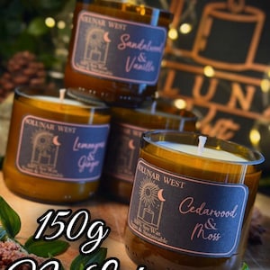 May include: Four glass jar candles with labels reading "Sandalwood & Vanilla", "Lemongrass & Ginger", and "Cedarwood & Moss". The candles are amber-colored with white wicks. The text "150g No Lid" is also visible.