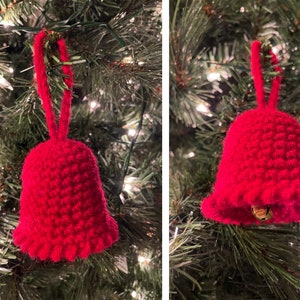 May include: A red crocheted bell ornament hanging on a Christmas tree. The bell has a loop at the top for hanging and a small jingle bell inside.