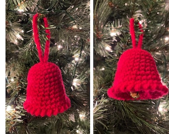 May include: A red crocheted bell ornament hanging on a Christmas tree. The bell has a loop at the top for hanging and a small jingle bell inside.