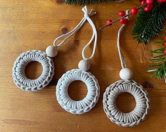 May include: Three crocheted wreaths with wooden beads and twine hangers. The wreaths are beige and brown.