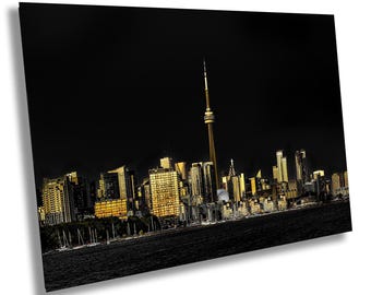 May include: A night view of the Toronto skyline featuring the CN Tower illuminated in gold against a deep black sky. The city buildings are lit with warm yellow lights, reflecting over the dark water in the foreground of the urban landscape.