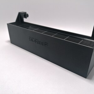 May include: A black plastic 3D printed fan shroud with a grill and the text "3DReef" printed on the front.