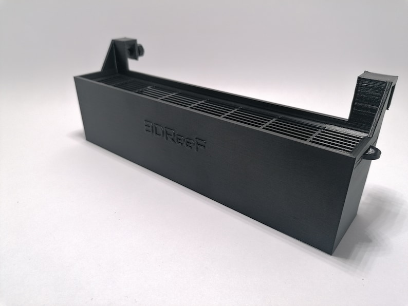 May include: A black plastic 3D printed fan shroud with a grill and the text "3DReef" printed on the front.