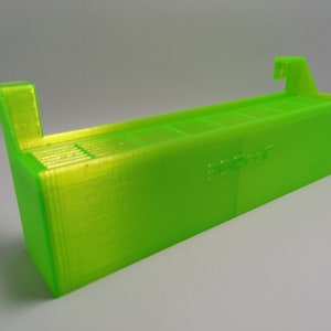 May include: A bright green 3D printed storage box with a label that says "3D Print". The box has a series of slots for holding small items.