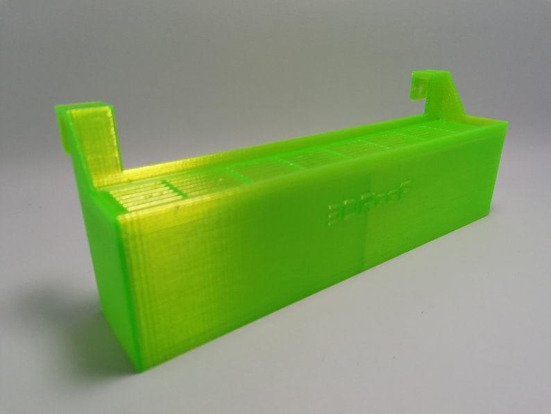 May include: A bright green 3D printed storage box with a label that says "3D Print". The box has a series of slots for holding small items.