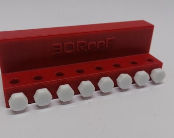 May include: A red plastic holder with the text "3DReef" printed on it. The holder has ten holes and white plastic pegs inserted into the holes.