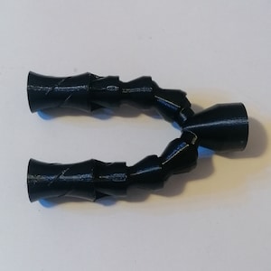 May include: A black, Y-shaped flexible hose with ribbed sections and flared ends. The hose is made of a smooth, possibly plastic material. The design suggests it is for directing fluids or gases.