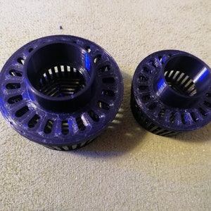 Könnte beinhalten: Zwei schwarze Plastik-Filterkörbe mit einem Gittermuster. Der größere Korb hat einen Durchmesser von etwa 10 cm und der kleinere Korb einen Durchmesser von etwa 7,5 cm.