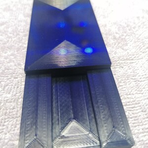 May include: A dark blue, geometrically shaped, 3D printed object with a textured surface.