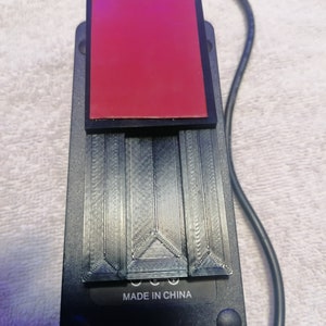May include: A black power adapter with a red adhesive pad on top. The adapter has a black cord and the text "MADE IN CHINA" printed on the bottom.