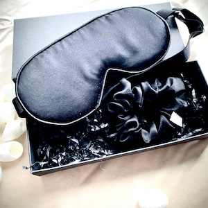 May include: A black silk sleep mask, a black silk scrunchie, and white silk cocoons in a black gift box with black shredded paper.